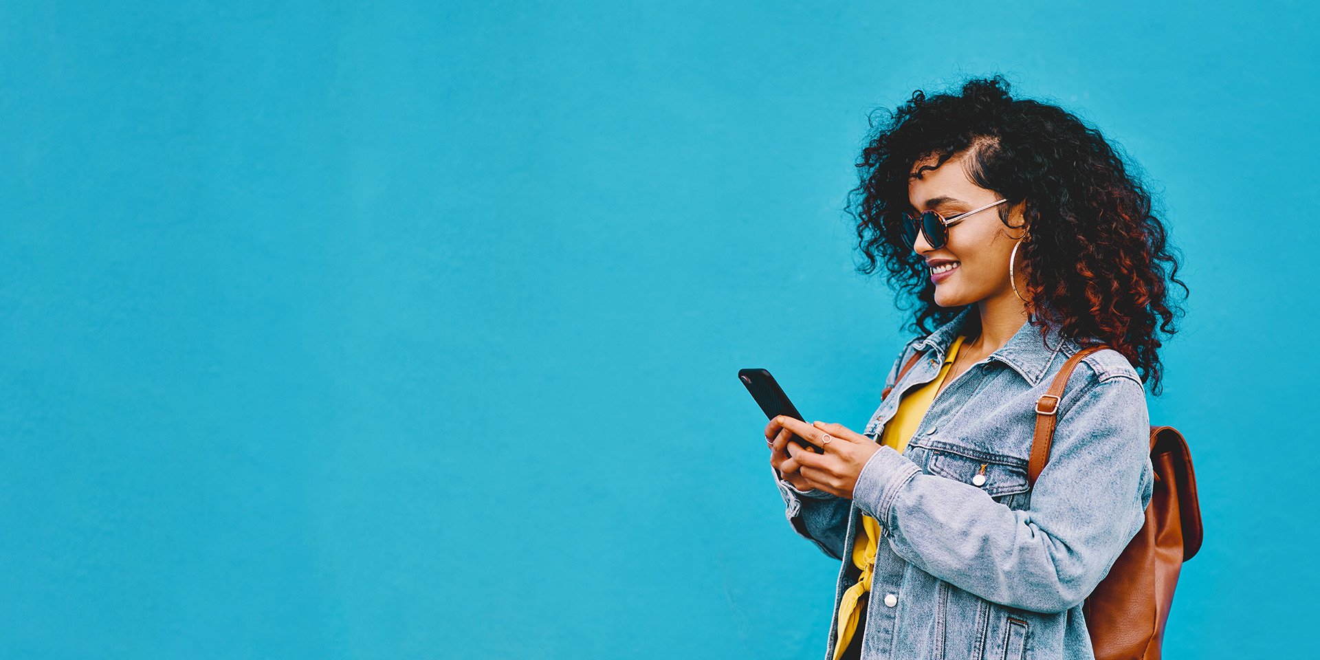 A joyful customer effortlessly manages her finances using Desert Financial overdraft services, smiling while checking her phone for account updates.