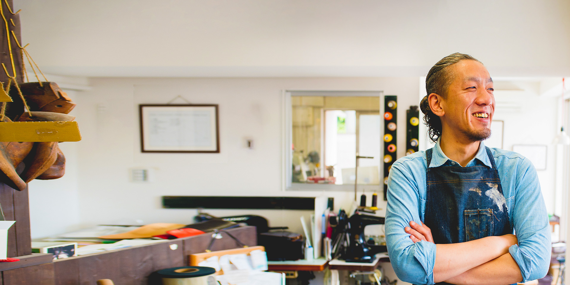 A joyful artist in a paint-smeared apron, standing in his studio with his arms crossed.