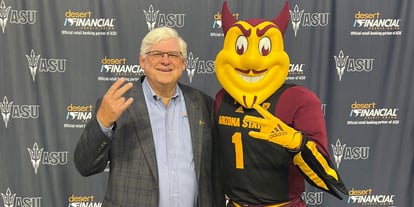 Jeff Meshey (left) proudly displaying the 'Fork 'em Devils' hand sign, standing alongside Sparky the Sun Devil Mascot, against a backdrop celebrating the partnership between Desert Financial and Arizona State University.