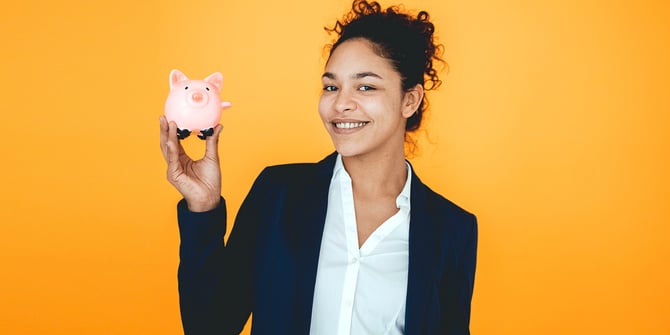 A happy businesswoman holding a small piggy bank in her right hand. 